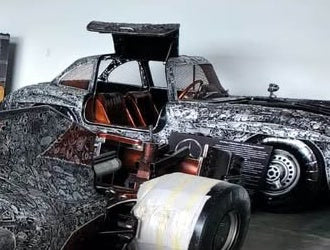 Gullwing-inspired full-scale recycled metal coupe with doors raised — fabrication studio